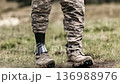 Military personnel walks confidently on grass with a prosthetic leg during a sunny afternoon outside 136988976