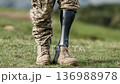 Military personnel walks confidently on grass with a prosthetic leg during a sunny afternoon outside 136988978