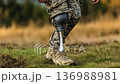Military personnel walks confidently on grass with a prosthetic leg during a sunny afternoon outside 136988981