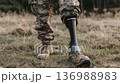 Military personnel walks confidently on grass with a prosthetic leg during a sunny afternoon outside 136988983