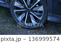 Rotation of the wheel of an electric car in place. Flat tire on a sleek vehicle during a muddy outdoor adventure at sunset 136999574