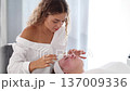 A professional skincare specialist applies a cooling gel on a client's face with a gentle spatula, focusing on precise treatment. 137009336