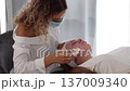 The beautician wearing a protective mask performs a detailed skincare treatment on a client, emphasizing cleanliness and care. 137009340
