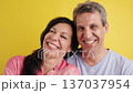 Happy middle-aged couple laughing together against yellow background 137037954