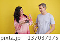 Mature couple exchanging a surprise gift on yellow background 137037975