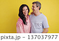 Happy middle-aged couple laughing together against yellow background 137037977