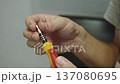 Male hand inserts metallic magnetized bit into manual screwdriver, closeup. Preparation of tip with miniature cross for work with small details. 137080695
