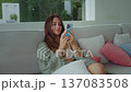 Young woman using smartphone while relaxing on sofa at home enjoying calm smartphone lifestyle and comfort indoors. Smartphone use shows modern digital lifestyle leisure time and mobile connection 137083508