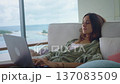 Slow living woman works calmly on laptop while resting on sofa at home. Slow living lifestyle reflects mindful productivity comfort planning ideas and peaceful modern work environment. 137083509