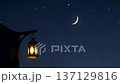 A tranquil night scene featuring a glowing lantern and crescent moon. 137129816