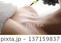 Cosmetologist in gloves applying a liquid vitamin serum on the neck and clavicle area in a spa 137159837