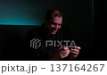 Young man intensely playing a mobile video game on his smartphone in a dark room with blue light 137164267