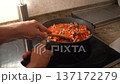 Chef stirring a simmering homemade meat and tomato ragu in a black pan on an induction stove 137172279