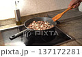 Male hand stirring chopped meat and onion with a wooden spatula in a hot pan on an induction cooktop 137172281