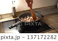 Male hand stirring diced meat and onion with a wooden spoon in a pan on an induction stove 137172282