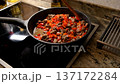 Woman preparing a delicious beef stew with red bell peppers in a hot skillet on an induction stove 137172284