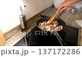 Man's hand stirring diced meat and onions with a wooden spatula in a non-stick frying pan 137172286