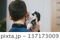 Young boy holding and interacting with a small black and white puppy indoors 137173009