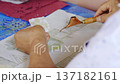 Close up of people using Tjanting tools to dip hot wax for traditional Batik making process. 137182161