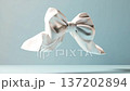A white bow rotates freely in the air against a light blue backdrop. The movement shows the flowing fabric and its shape in an interesting way. Details of design are clear 137202894
