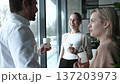 Three people are smiling and holding cups of coffee 137203973