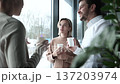 Three people are sitting in a cafe, each holding a cup of coffee 137203974
