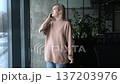 A woman is talking on her cell phone while standing in front of a plant 137203976
