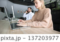 A woman is sitting at a desk with a laptop open in front of her 137203977