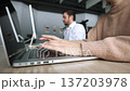 A woman is typing on a laptop while a man looks on 137203978
