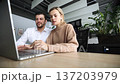 A man and a woman are looking at a laptop together 137203979