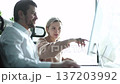 A man and a woman are working on a computer together 137203992