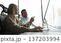 A man and a woman are sitting at a desk with a laptop in front of them 137203994