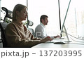 Two people are working on a computer at a desk 137203995
