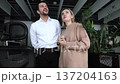 A man and woman are standing in front of a plant 137204163