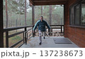 Man performing jumping jacks on wooden porch outdoors 137238673