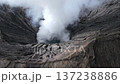 Aerial view of Mount Bromo crater in East Java, Indonesia, with thick volcanic steam rising from the caldera. Perfect for themes of nature, travel, geology, and dramatic landscapes. 137238886