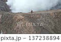 Aerial view of woman walking along the rim of steaming Mount Bromo volcano crater in Indonesia. Concept of nature, travel, adventure, and breathtaking landscapes. 137238894