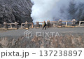 Aerial view of woman walking along the rim of steaming Mount Bromo volcano crater in Indonesia. Concept of nature, travel, adventure, and breathtaking landscapes. 137238897