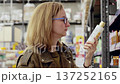 Customer choosing cosmetics in a supermarket, reading the composition and manufacturer's information. Shelves and products in the background 137252165
