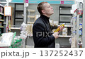 Customer in casual attire examines a cleaning product label while shopping in a supermarket, thoughtfully weighing options among various household items on the shelves 137252437