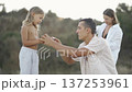 A caring father interacts with his daughter in a natural setting, highlighting family connection and warmth. The mother observes from behind, emphasizing togetherness and harmony 137253961