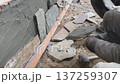 A builder faces the basement of a house with a wild stone. Flat for cladding, tabata on the construction site. 137259307