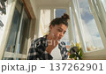 Woman finishing morning skincare ritual by bright window 137262901