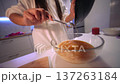 Hands pouring eggs into mixing bowl near wooden surface 137263184