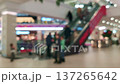 visitors walking through a modern shopping mall and riding an escalator 137265642