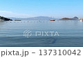 Wide-angle view of a calm, clear blue sea bay with gentle ripples. Sailboats and distant mountains sit under a bright sky at a peaceful coastal destination. High quality 4k footage 137310042