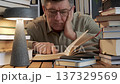 Mature man reading book and studying late at desk with lamp 137329569