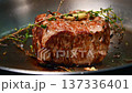 Beef steak searing in a pan with fresh thyme and garlic, showcasing the browning crust and rich juices, highlighting the cooking process in a kitchen setting 137336401