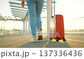 Woman confidently pulling a suitcase in an airport terminal. Back view 137336436