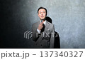A Japanese man in a suit giving a presentation using a pin microphone 137340327